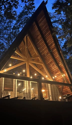 Cabaña en forma de A iluminada con guirnaldas de luces bajo un cielo nocturno azul intenso