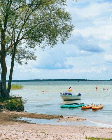 Sandy lake beach with kayaks and boats on a sunny summer day