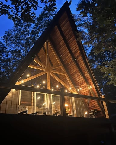 Chalet en A illuminé sous un croissant de lune, entouré de pins enneigés